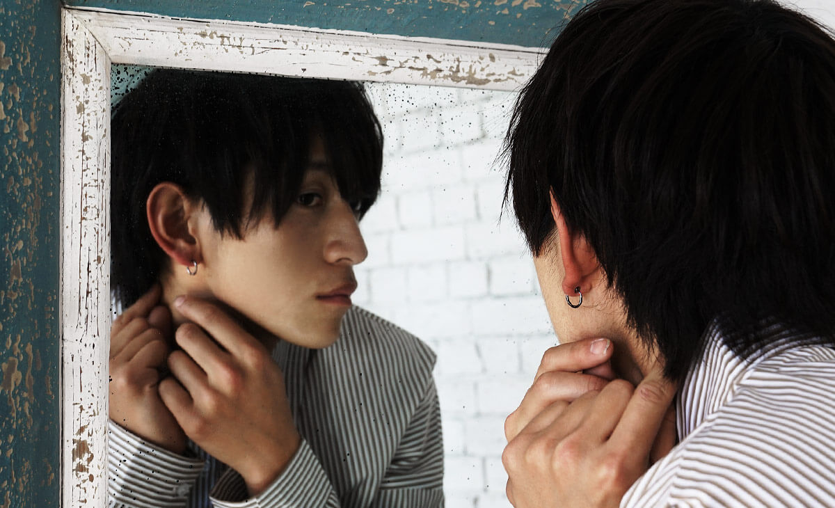 鏡を見ながらイヤーカフをつけるモデル